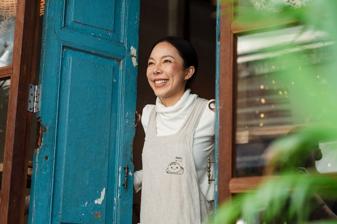 Happy small business cafe owner at her shop entrance