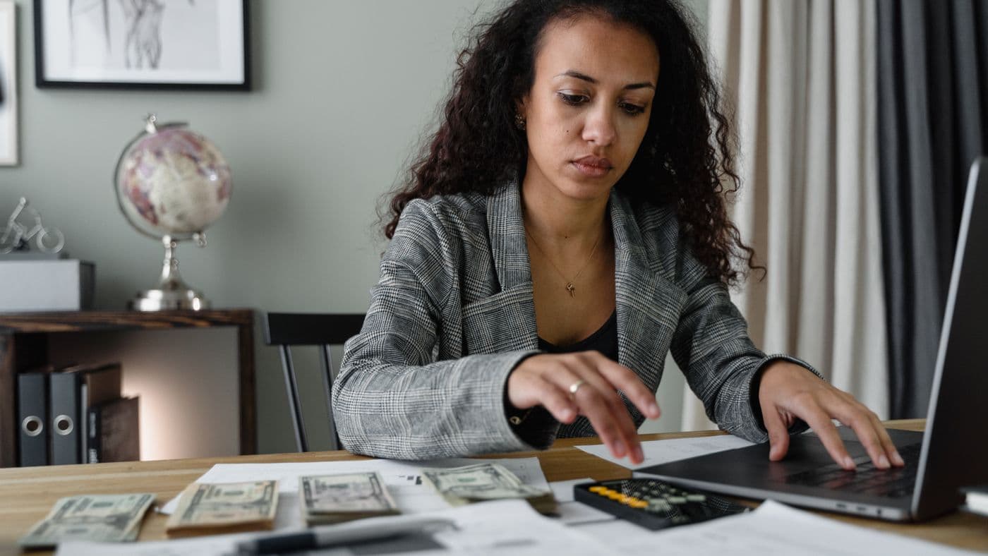 Small business owner reviewing finances on a laptop with calculator and payment records