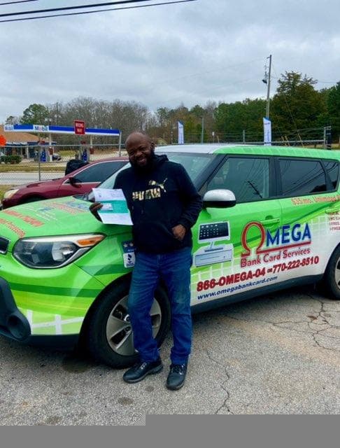 Merchant with Omega Bank Card Services branded vehicle and rewards materials